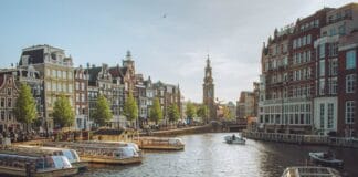 Kanał w Amsterdamie z łódkami wycieczkowymi i zabytkowymi kamienicami